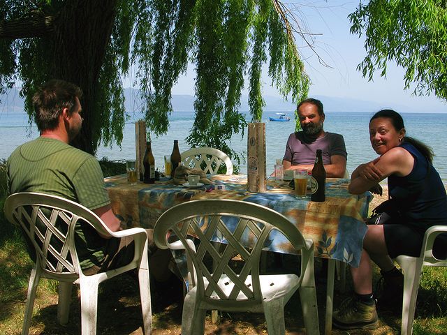 foto č. 133 - Ve stínu vrby čekáme na autobus zpátky do Ohridu, čekání si zpříjemňujeme chlazeným Skopskem, výhledem na jezero a na albánské hory.
