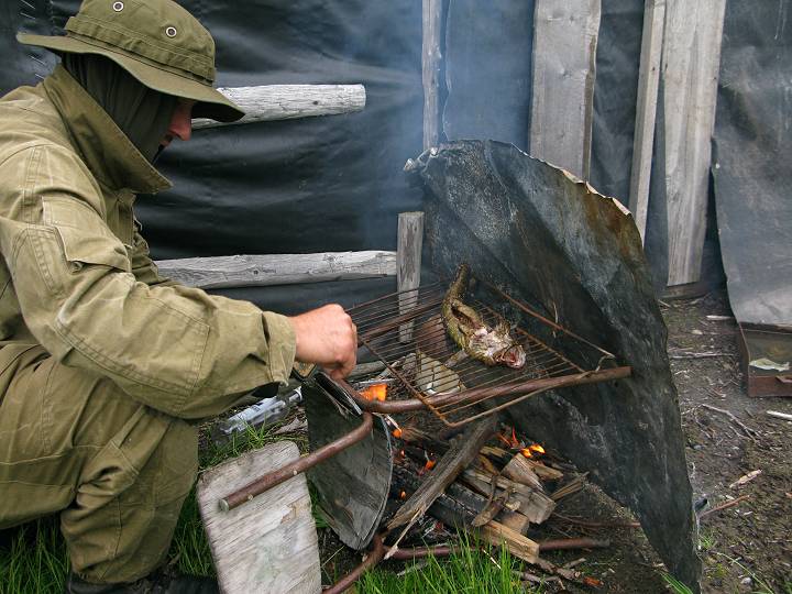 foto č. 030 - Bohouš opéká na grilu ze školní židle a roštu z ledničky rybu, kterou dostal od rybáře.
